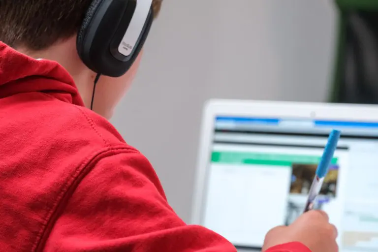 A person with headphones on looking at a laptop.