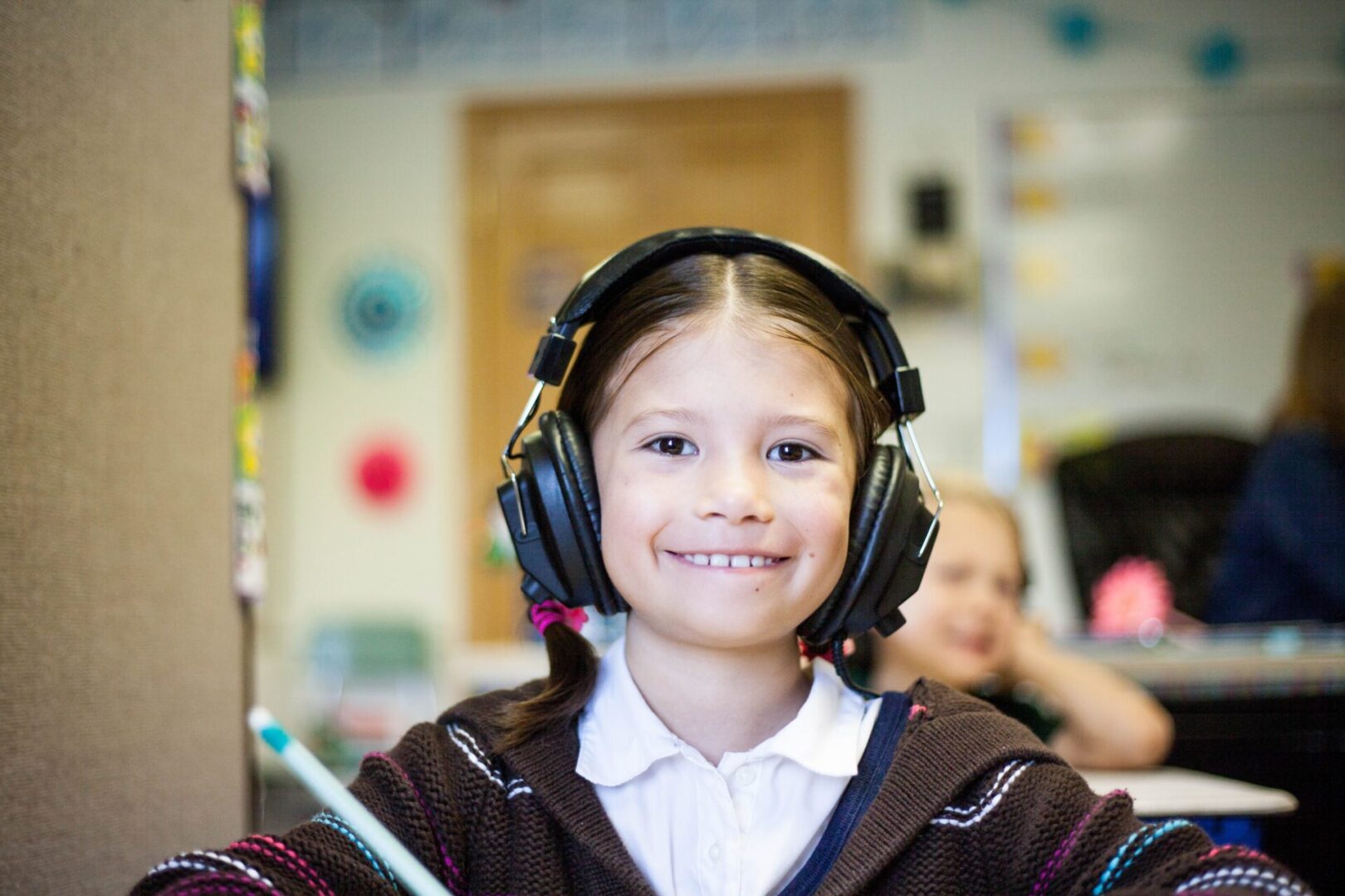 A girl with headphones on in a classroom.