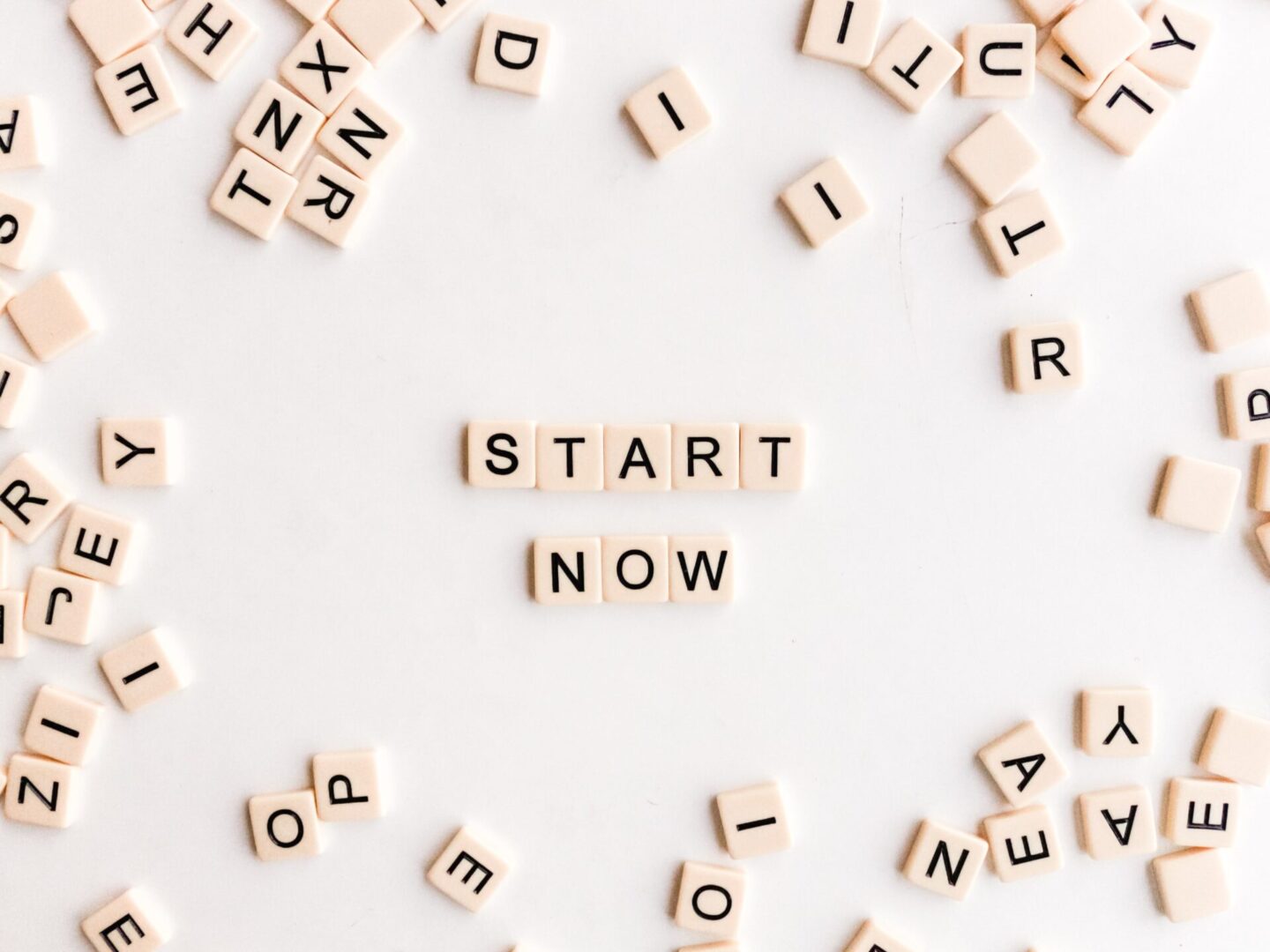 A white table topped with scrabble tiles that say " start now ".